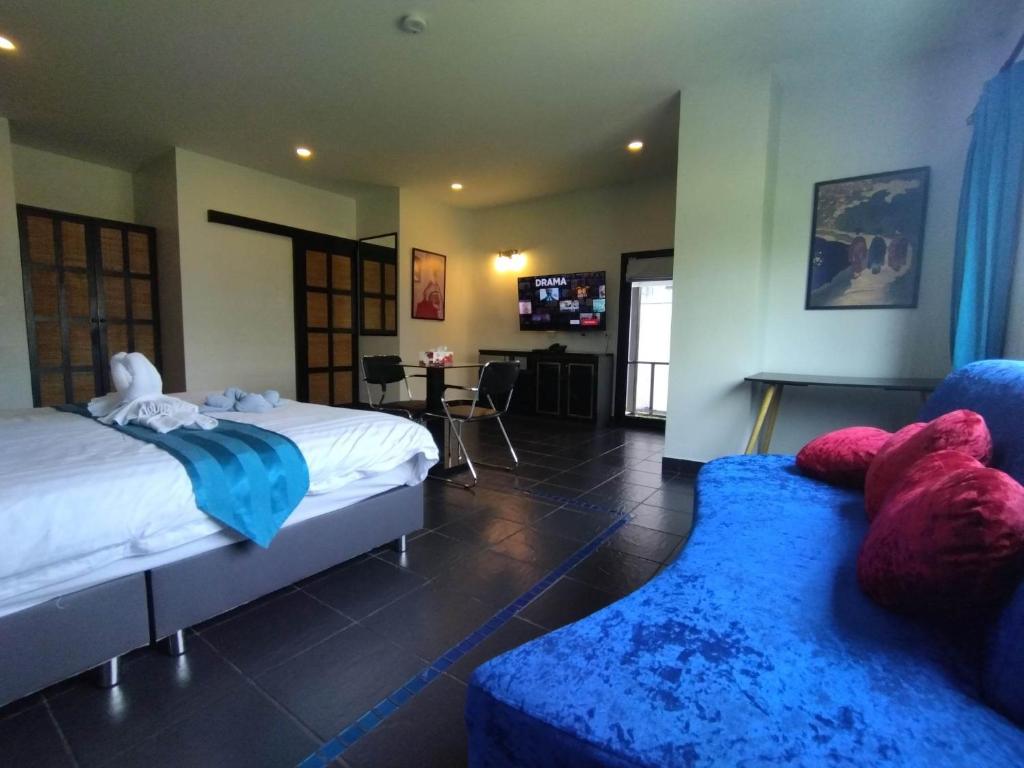 a hotel room with two beds and a blue couch at The Venue Residence - SHA Extra Plus in Pattaya South