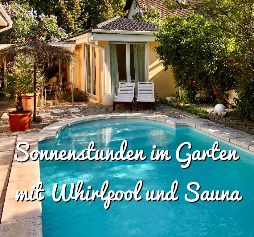 a swimming pool in a yard with two chairs and a house at Apartment TinyHouse mit Pool, Outdoor Whirlpool und Garten in Petershagen