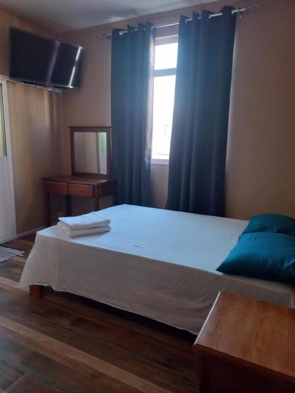 1 dormitorio con 1 cama con cortinas azules y ventana en En-suite Rooms in shared appartment, en Quatre Bornes
