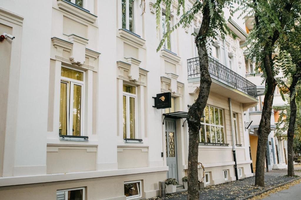 un edificio blanco con árboles delante de él en Artist hotel en Subotica