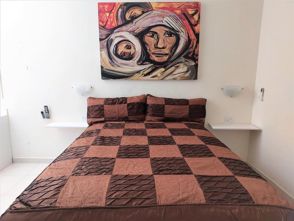 1 dormitorio con 1 cama con una pintura en la pared en Loft 25 excelente y comodo, cerca del vado del rio, consulado,CAS, galerias mall , cama queen , cocineta, en Hermosillo