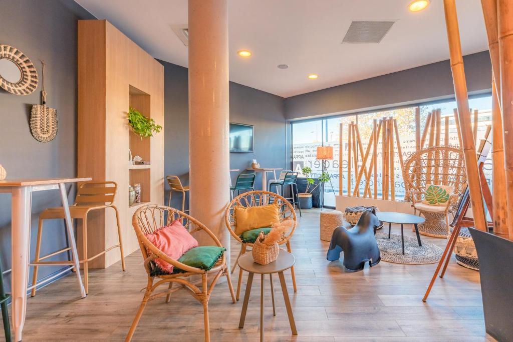 ein Wohnzimmer mit Stühlen, Tischen und einem Tisch in der Unterkunft Appart’City Confort Montpellier Millénaire in Montpellier