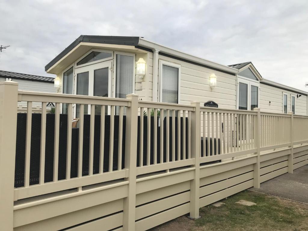 a house with a white picket fence at Hot Tub Accommodation North Wales Caravan in Rhyl