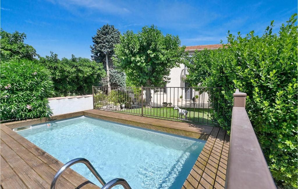 a swimming pool in a yard with a wooden deck at Nice Home In Vallabrgues With 3 Bedrooms, Wifi And Outdoor Swimming Pool in Vallabrègues