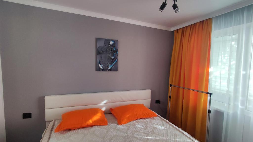 - une chambre avec un lit et deux oreillers orange dans l'établissement Уютная люкс квартира в центре, à Uralsk