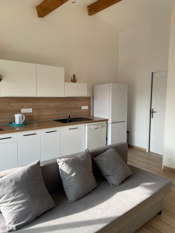 a kitchen with white cabinets and a couch with pillows at Cocon en Provence in Marignane