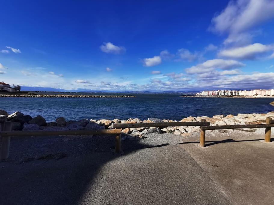 un banc assis sur le côté d'une masse d'eau dans l'établissement Joli studio cabine dans résidence en bord d'étang, au Barcarès