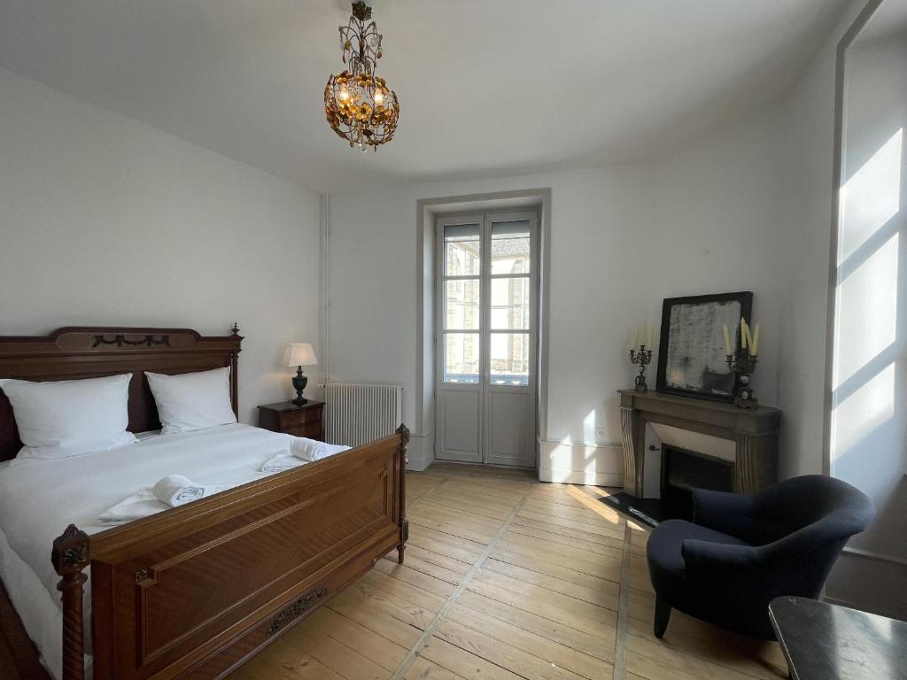 a bedroom with a bed and a chair and a chandelier at L&#39;appartement du Cellier in Pommard