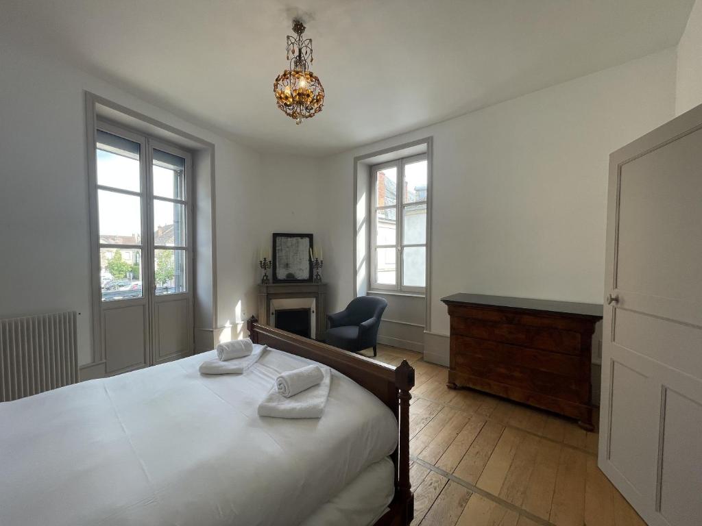 a bedroom with a bed and a chair and windows at L&#39;appartement du Cellier in Pommard