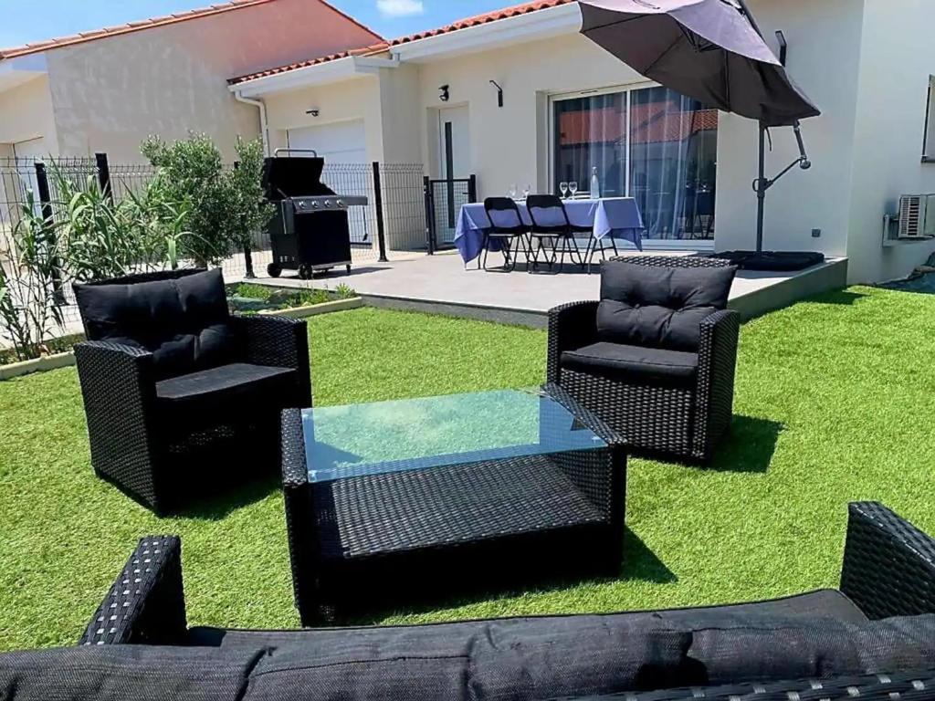 patio z krzesłami, stołem i parasolem w obiekcie Le Brasil - Maison 74 m - Calme avec terrasse Sud classée 3 étoiles w mieście Le Boulou