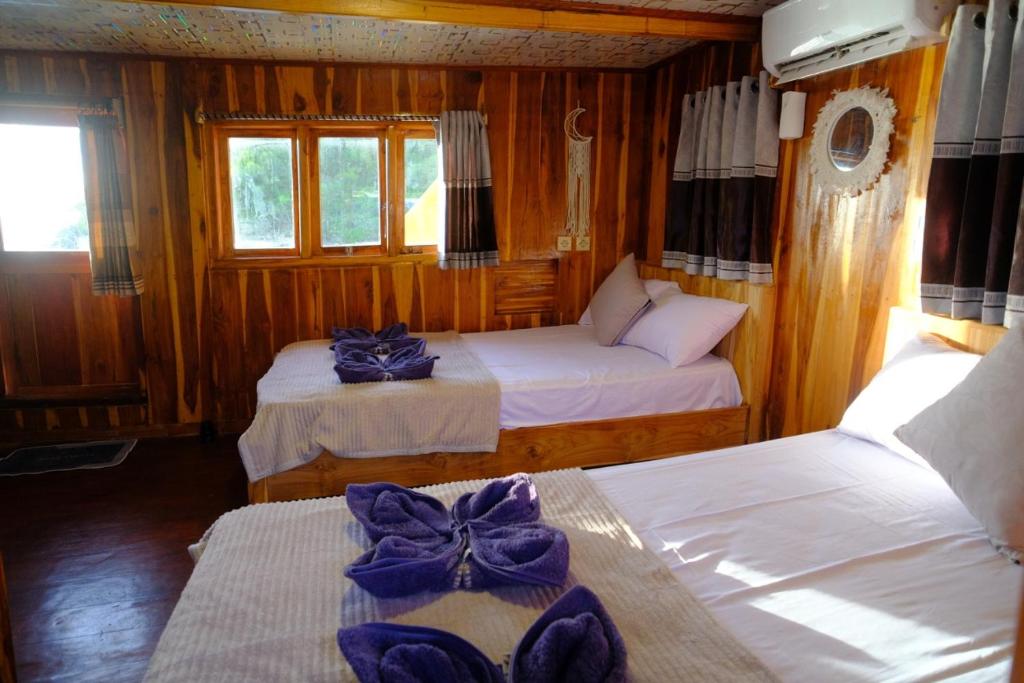 ein Schlafzimmer mit zwei Betten mit lila Bogen darauf in der Unterkunft Family labuan bajo in Labuan Bajo