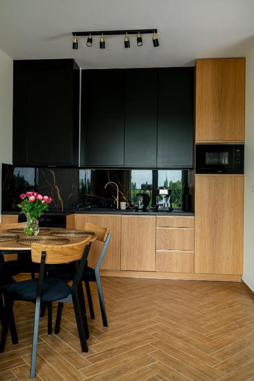 a kitchen with a table and a kitchen with black cabinets at Apartament Thaddeus 48 z tarasem in Zator