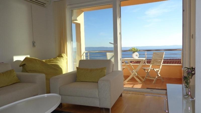 sala de estar con sofá, silla y balcón en Apartment Lara, en Makarska