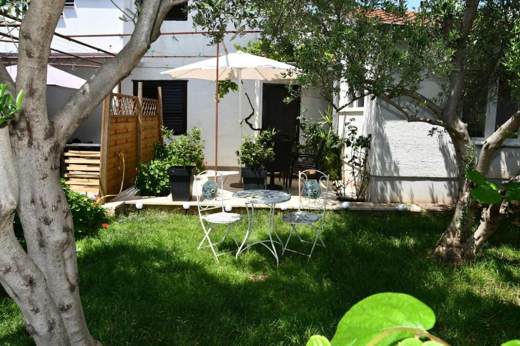un patio trasero con mesa, sillas y sombrilla en Apartmani Katarina 4+2, en Biograd na Moru