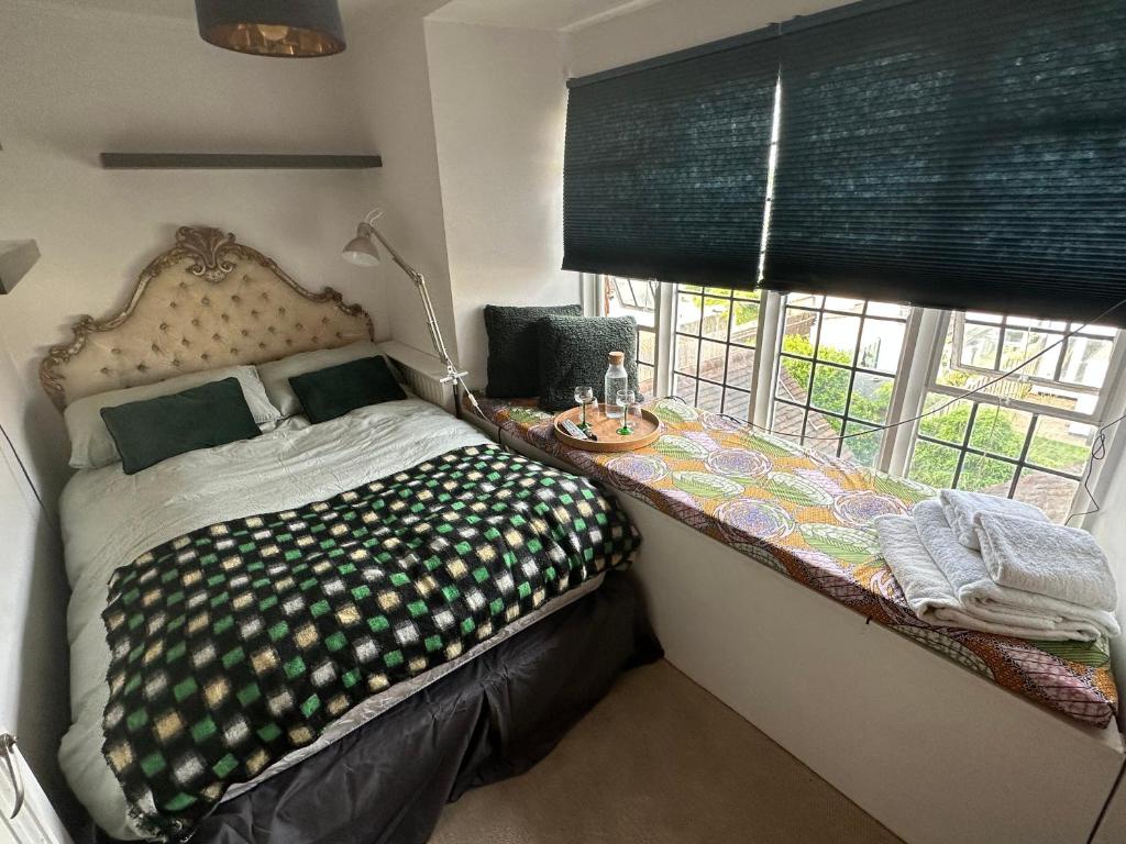 a bedroom with a bed with a table next to a window at Converted church in Beckenham