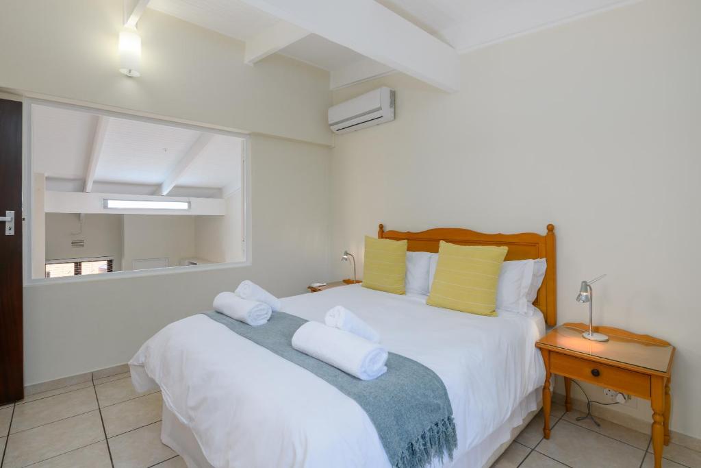 1 dormitorio con 1 cama con sábanas blancas y almohadas amarillas en San Lameer Villa 3501 - 2 Bedroom Classic - 4 pax - San Lameer Rental Agency, en Southbroom