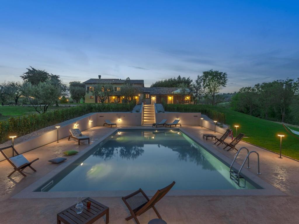 une piscine avec des chaises et une maison en arrière-plan dans l'établissement Inviting Holiday Home in San Costanzo with Swimming Pool, à San Costanzo
