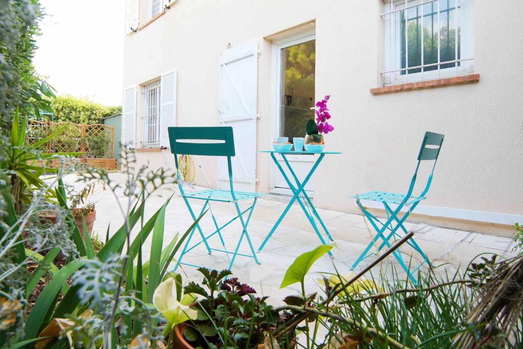 two blue chairs and a table in a garden at Nice House Rent in Saint-Laurent-du-Var