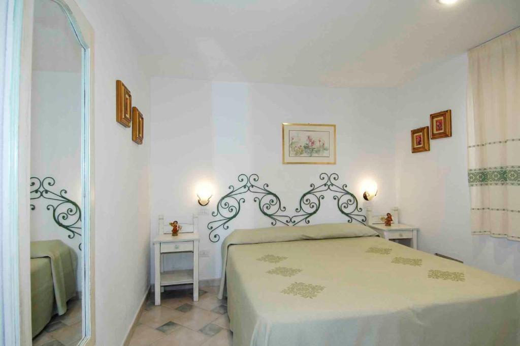 a white bedroom with a bed and two tables at Sardegna Beach Cala Reale in Santa Marinella