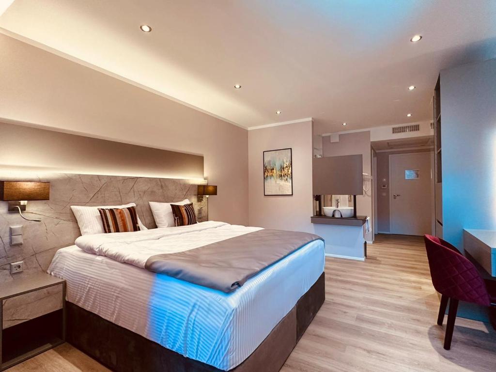 een grote slaapkamer met een groot bed en een bureau bij MEA HOTEL TRIER in Trier