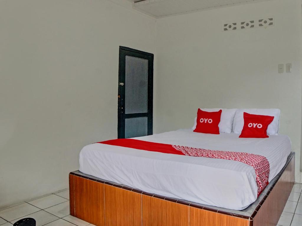 OYO 92579 Hotel Mutiara في بيماتانغسياتار: غرفة نوم عليها سرير ومخدات حمراء