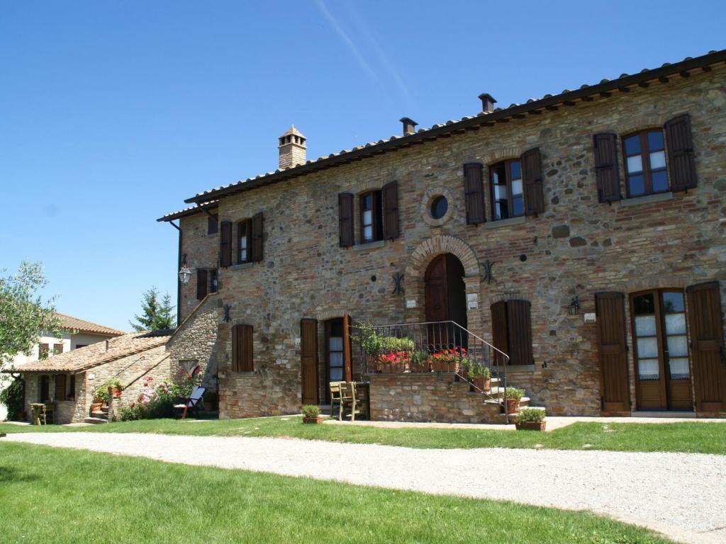 ein großes Steingebäude mit einem Rasenhof in der Unterkunft Nice apartment with pool and beautiful garden in Montone