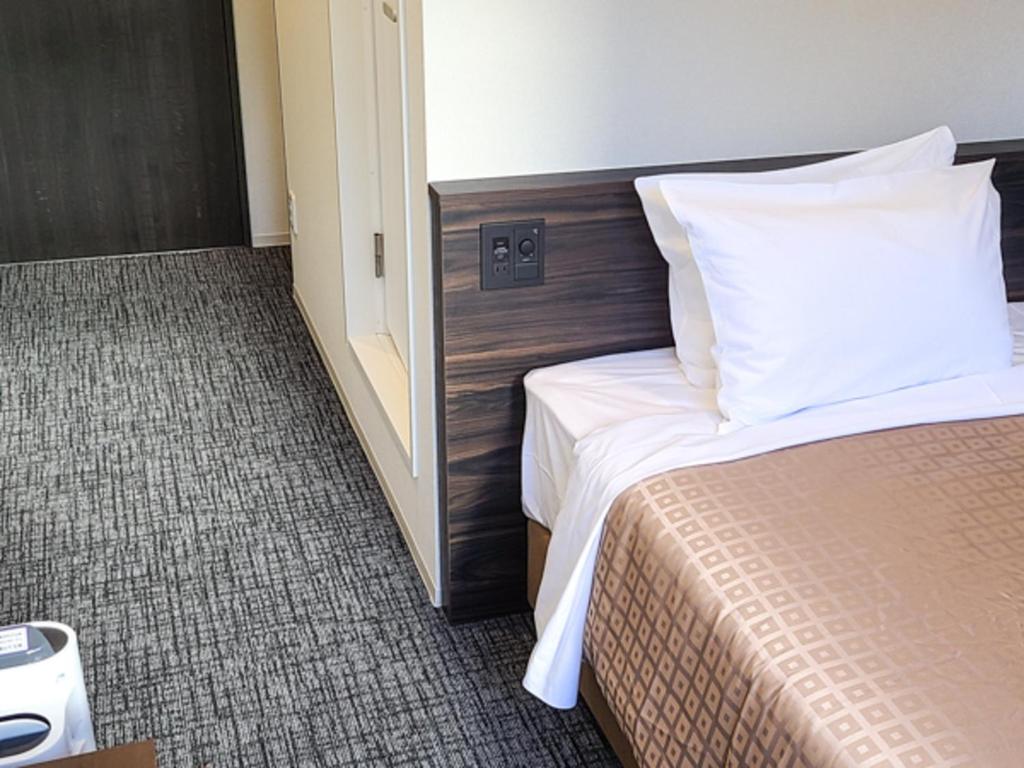 Postel nebo postele na pokoji v ubytování Hotel Livemax Premium Nagano Ekimae
