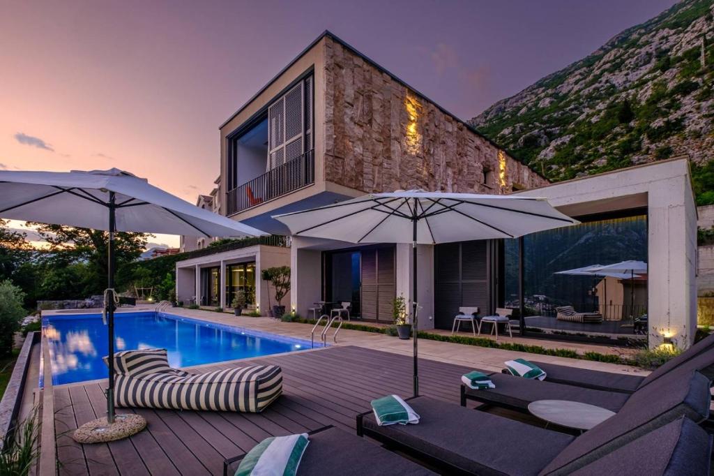 a house with a swimming pool with umbrellas at New luxury villa with 17m pool and bay view in Kotor