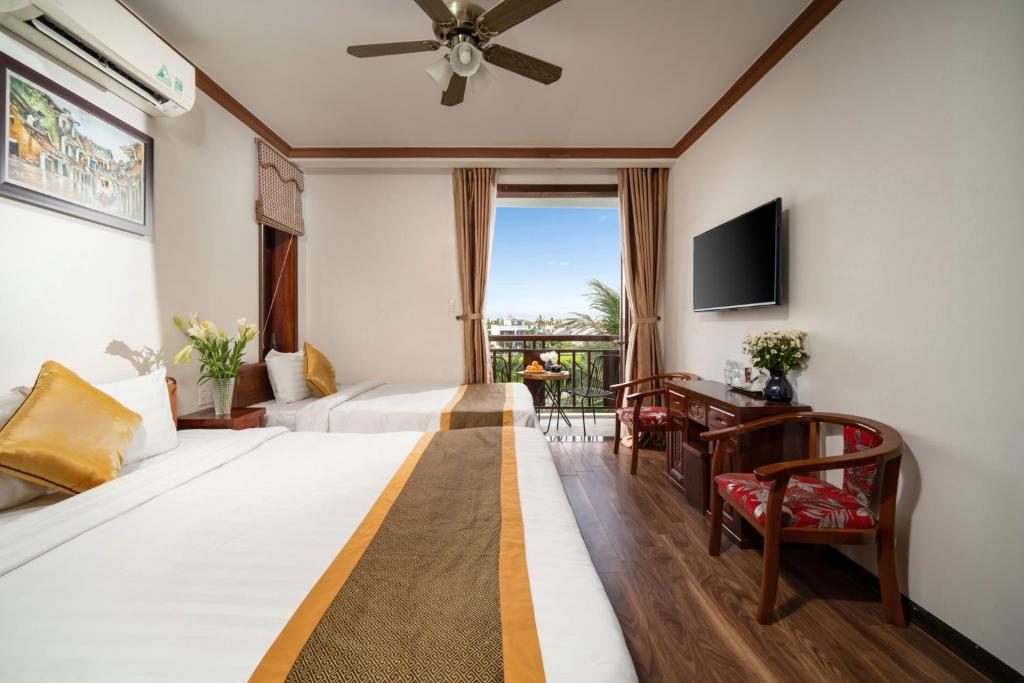 um quarto de hotel com duas camas e uma televisão em RAON Hoi An - STAY 24H em Hoi An