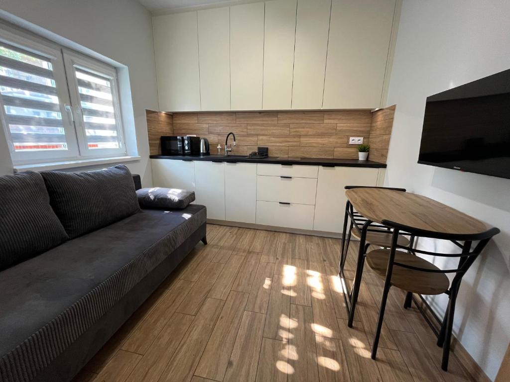 a living room with a couch and a table and a kitchen at Apartament Wojska Polskiego 35 in Wadowice