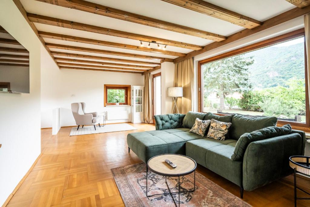 un soggiorno con divano verde e ampia finestra di Cottage 110 a Wösendorf