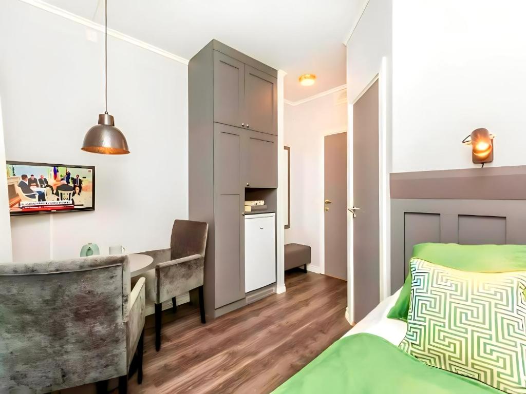 a bedroom with a bed and a desk and a kitchen at Oslo Airport Apartments in Gardermoen