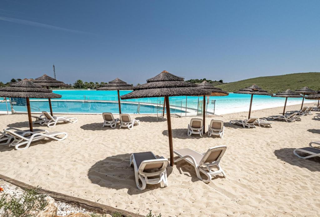 eine Gruppe von Stühlen und Sonnenschirmen am Strand in der Unterkunft Alcazaba Lagoon 2425 Luxury private beach in Estepona