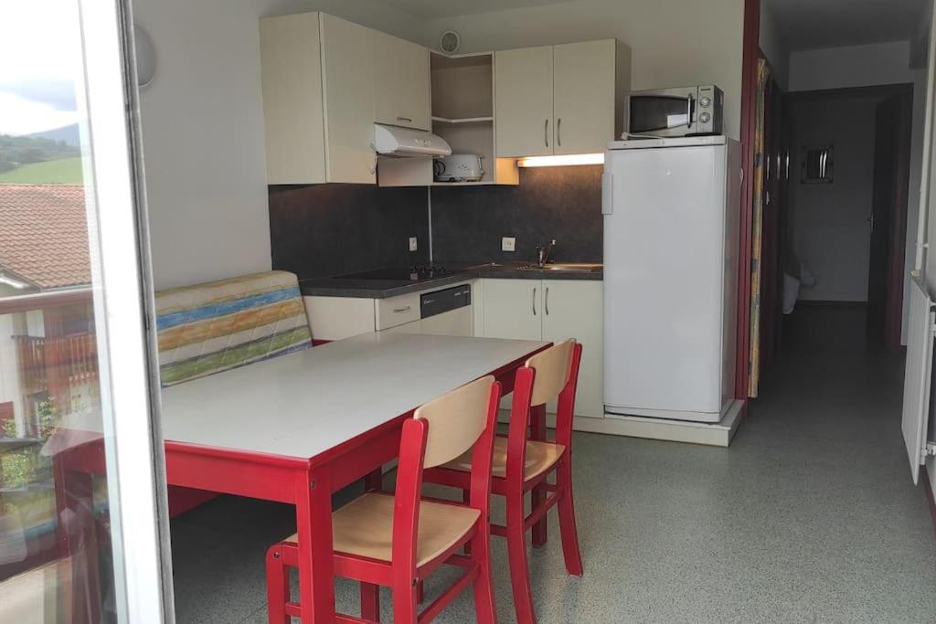 eine Küche mit einem Tisch und Stühlen sowie einem Kühlschrank in der Unterkunft Adour Piscine Vue Montagnes in Souraïde