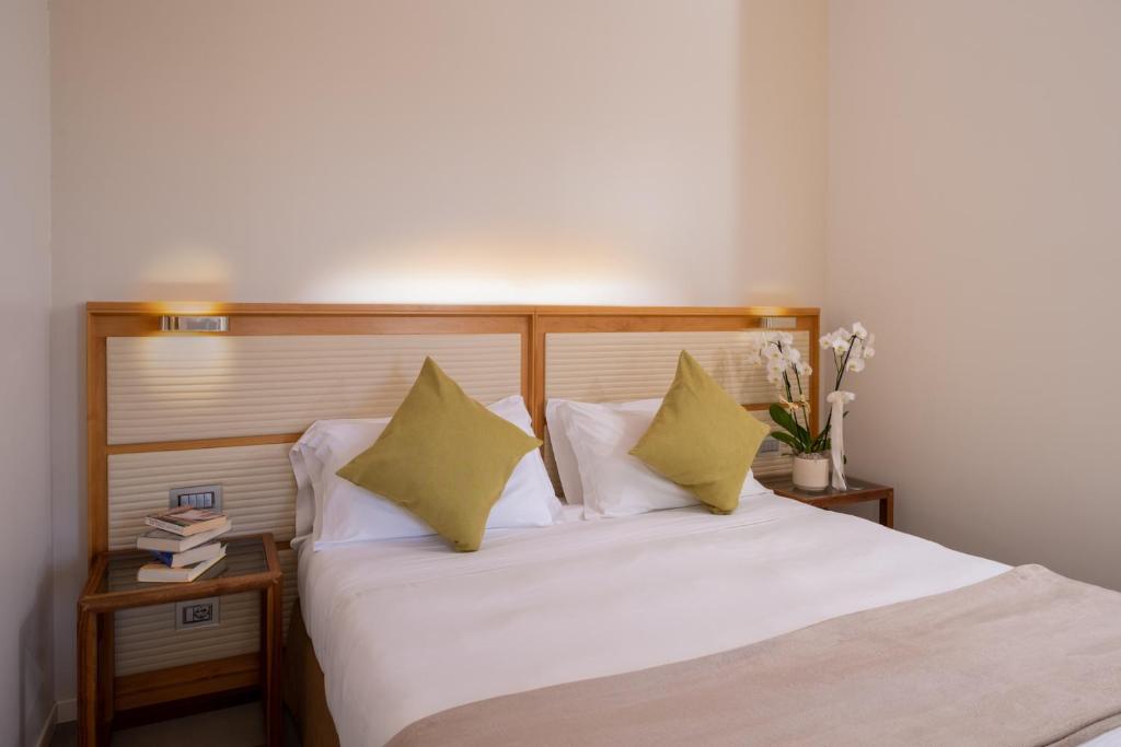 a bedroom with a bed with white sheets and yellow pillows at The Ziba Hotel & Spa in Peschiera del Garda