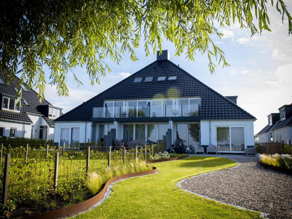 une maison avec un toit en gambrel et un jardin dans l'établissement Bright apartment within walking distance of the Sneekermeer, à Offingawier