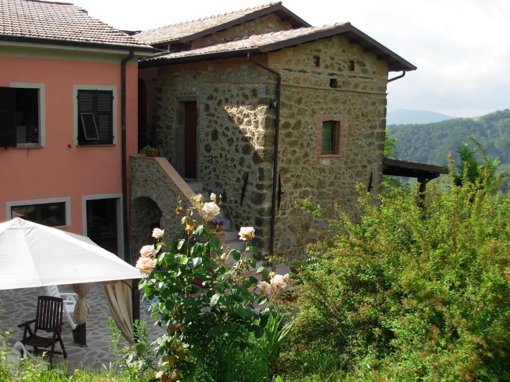 um edifício de pedra com um guarda-chuva em frente em Holiday home in Canossa with Swimming Pool Garden Barbecue em Mulazzo