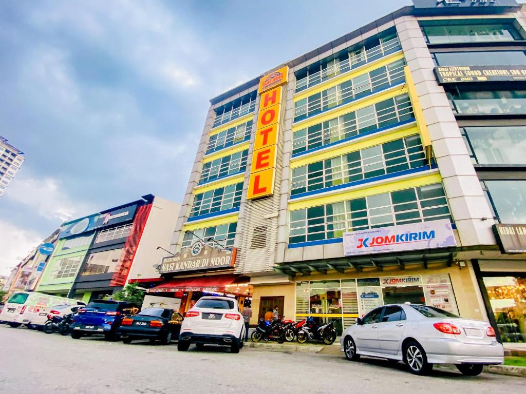 Un grand bâtiment avec des voitures garées devant lui dans l'établissement Sun Inns Hotel Puchong, à Puchong
