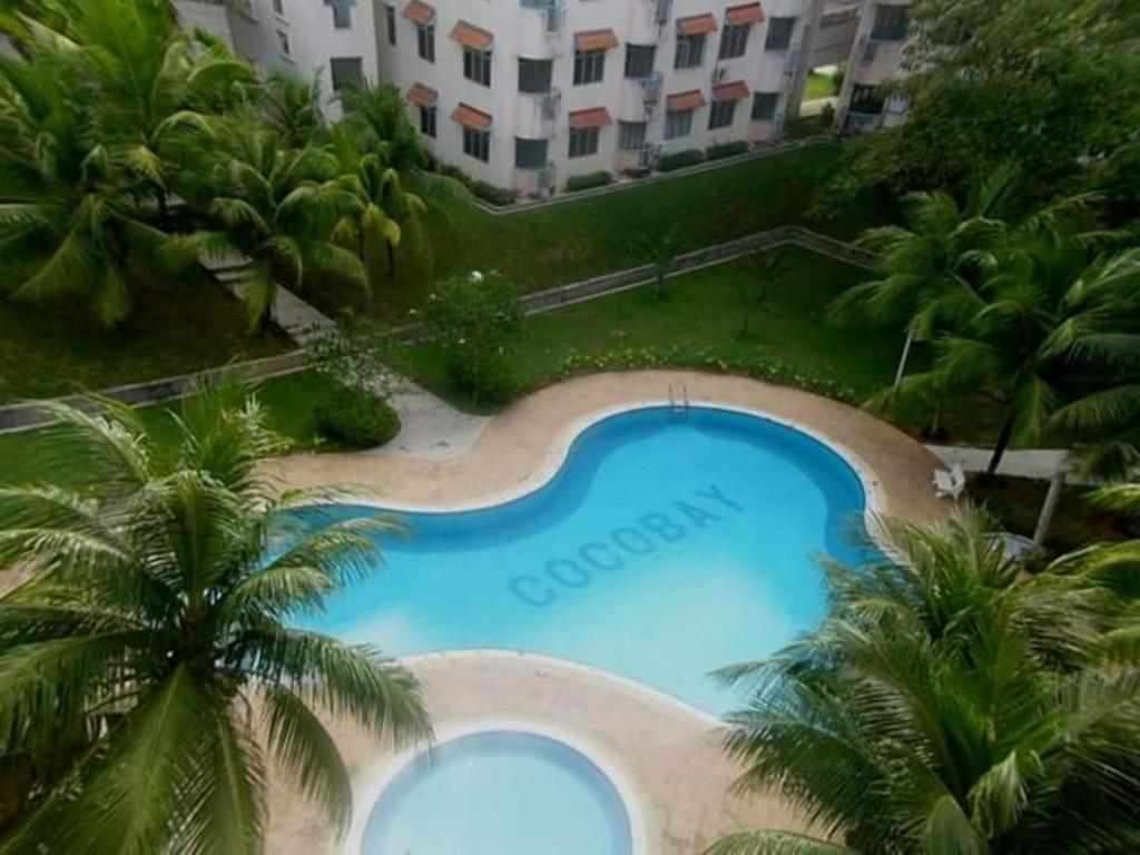 an overhead view of a large swimming pool with palm trees at Relaxing Retreats at Cocobay Apartments in Port Dickson