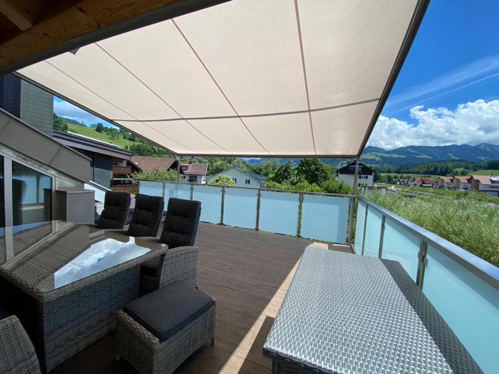 a patio with a table and chairs and a large umbrella at Berg Fux - Zwei Ferienhäuser mit je 5 und 6 Schlafzimmern mit eigener Dachterrasse - fantastischem Bergblick - Weber Gas Grill in Sonthofen