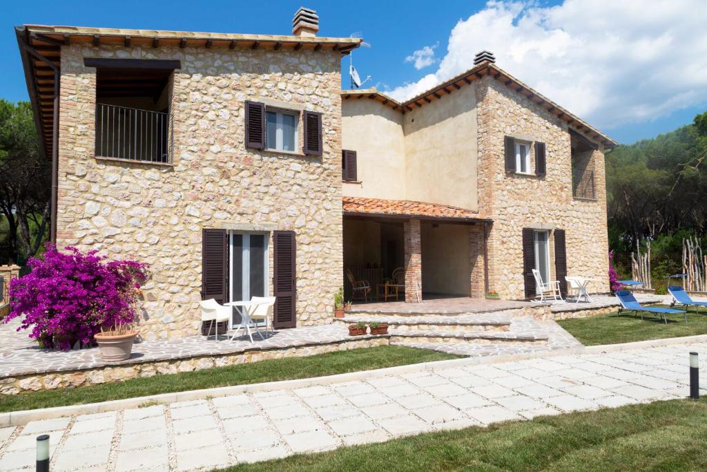 a large stone house with a patio and yard at Dimora La Fiumara in Marina di Grosseto