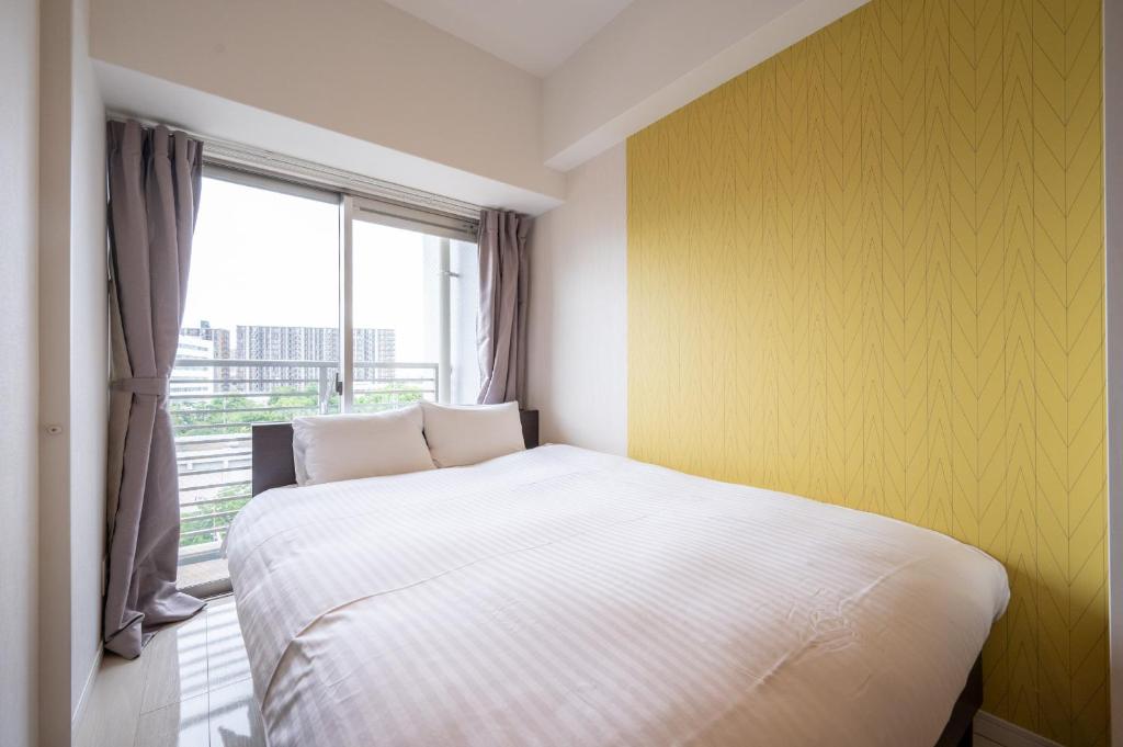 a bedroom with a white bed and a window at Residence Hotel Hakata 8 in Fukuoka