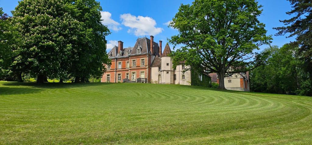 une grande maison avec une grande pelouse dans l'établissement Château de Montpatey, à Couches