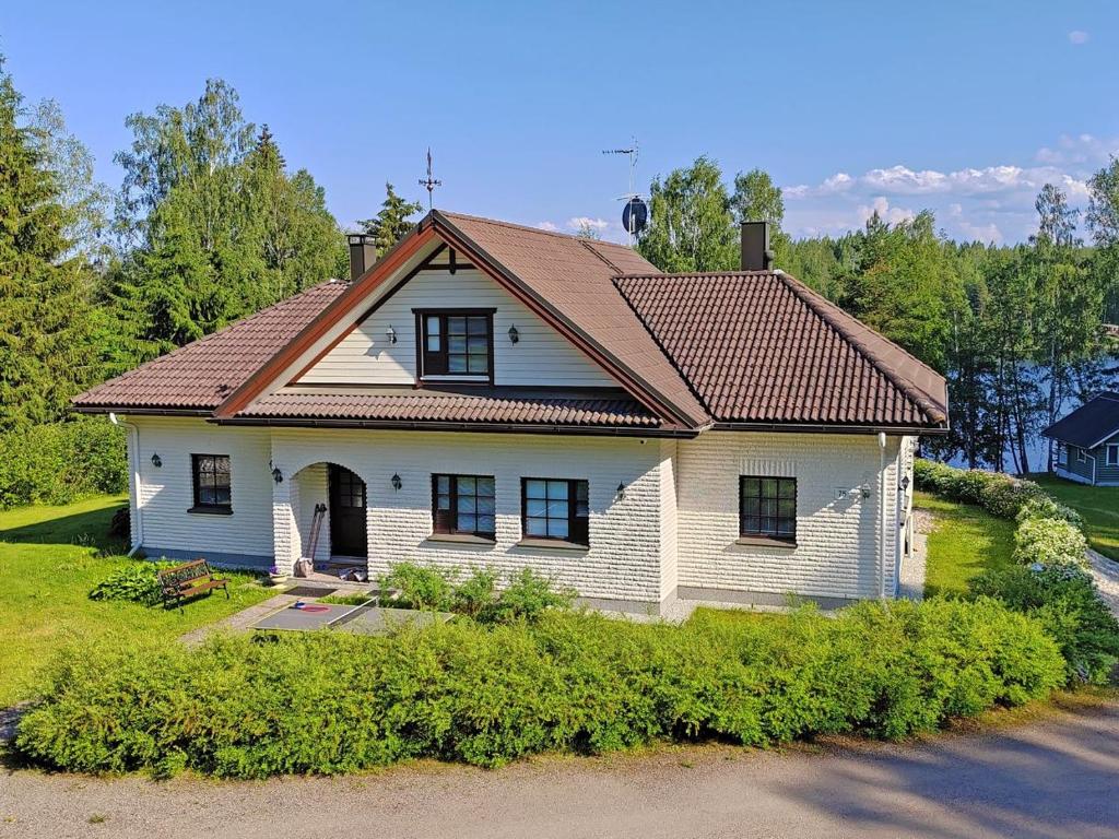 a white house with a brown roof at Villa Grinberg in Mäntyharju