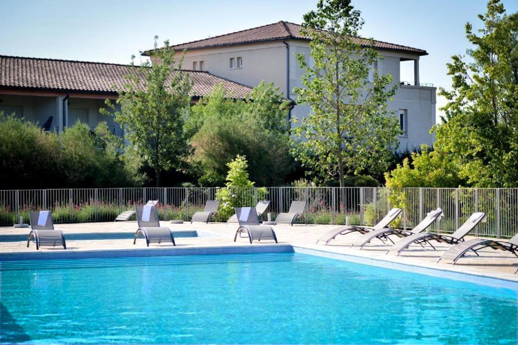 una piscina con sedie a sdraio accanto a un edificio di La Résidence du Château de Jouarres ad Azille