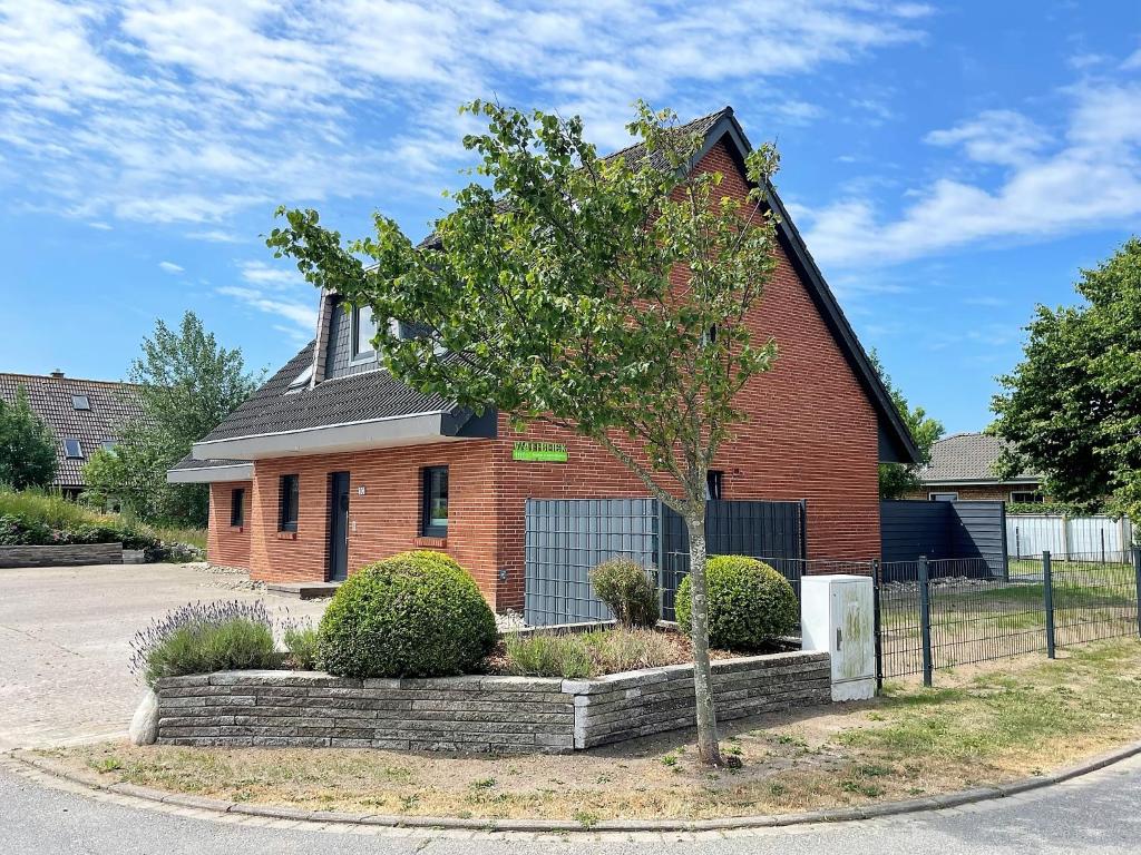 a red brick house with a tree in front of it at Wattblick in Dagebüll