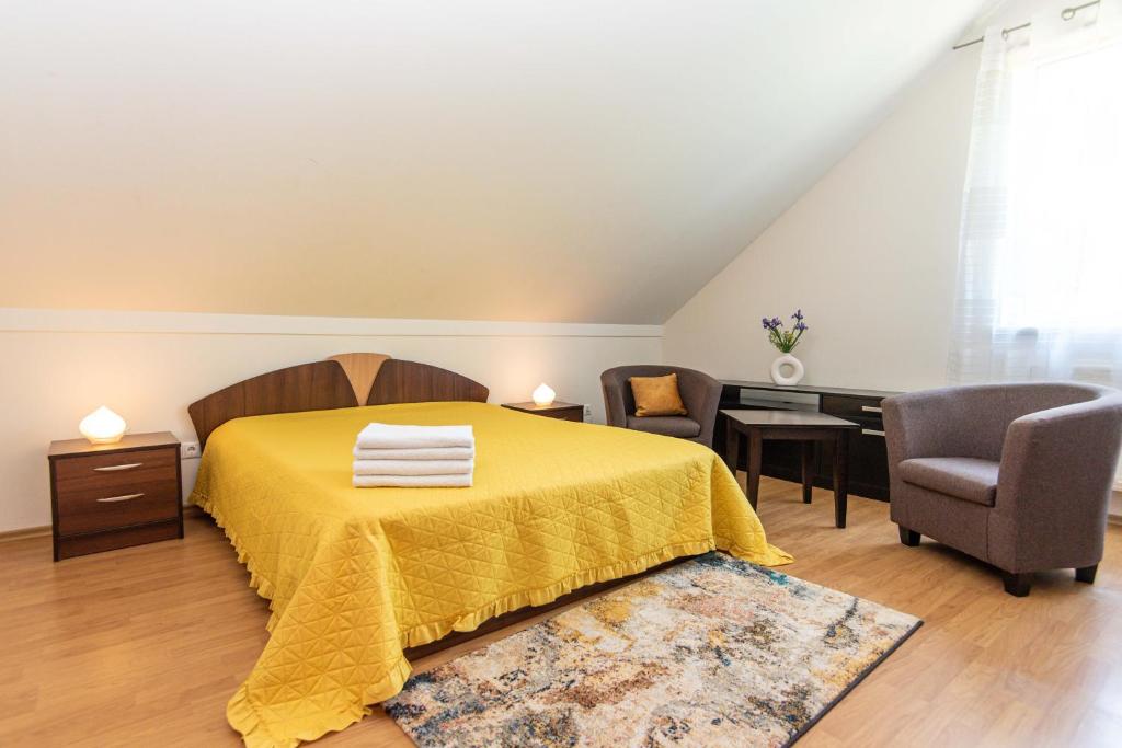 a bedroom with a yellow bed with a desk and chairs at Guest House Pasaulio Kraštas in Palanga
