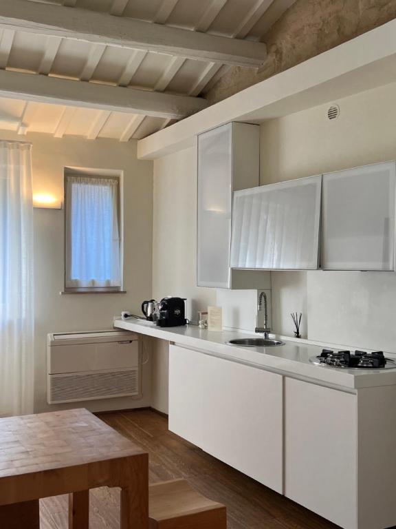 una cocina con armarios blancos y una mesa. en Urbino Apartment - Urban Retreat, en Urbino