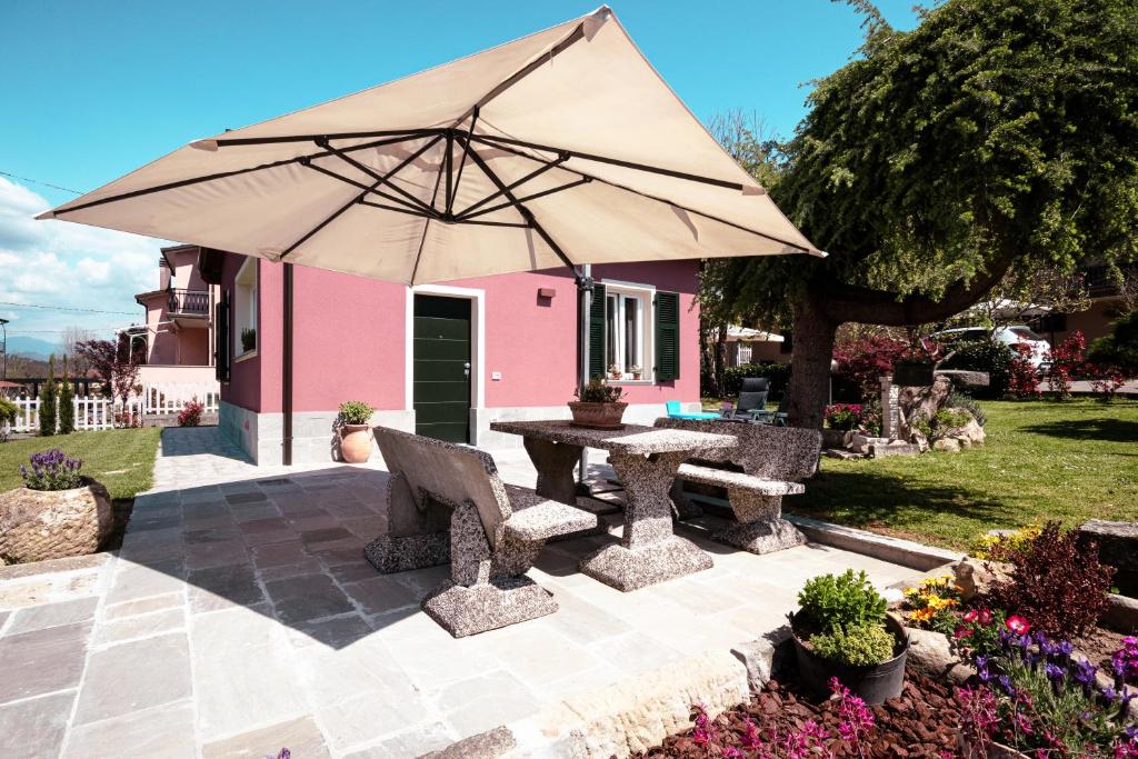 a picnic table with an umbrella in front of a pink house at La Casetta in Riccò del Golfo di Spezia