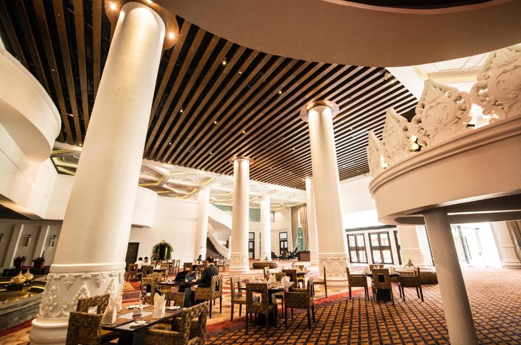 a dining room with tables and chairs in a building at Rose Garden Hotel in Yangon
